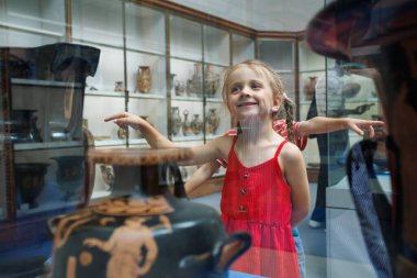 Çocuklar, kültür okulu gezisinde cam bir gösteride depolanan tarihi eşyalara hayran kaldılar.