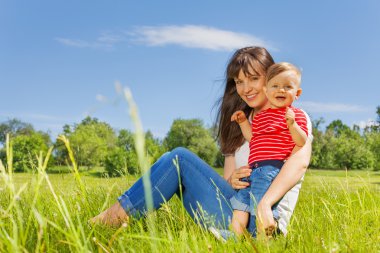 Bebek ve annesi birlikte çayırda gülümseyen