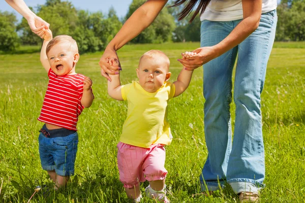 Glückliche Kleinkinder lernen gehen, indem sie Mütter an den Händen halten — Stockfoto