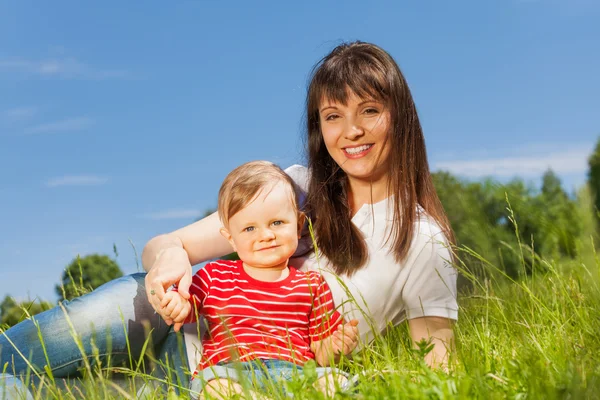 Kleine schattige baby en zijn mummie zitten in weide — Stockfoto