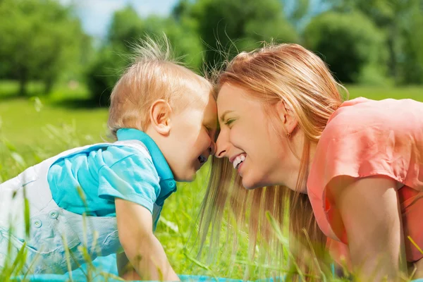 Sorrindo mãe e seu filho no campo verde — Fotografia de Stock