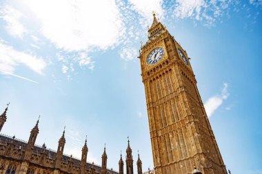 İkonik Big Ben saat kulesi açık mavi bir gökyüzüne karşı dimdik duruyor, göz kamaştırıcı mimarisini İngiltere 'nin canlı Londra şehrinde sergiliyor.,
