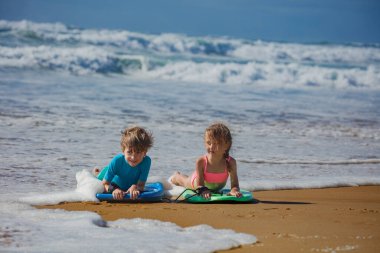 İki çocuk sığ sularda, tatilde sığ sularda uzanıyorlar, dalgaların tadını çıkarıyorlar, sahilde gün ışığının tadını çıkarıyorlar, arkadaşlarıyla ve aileleriyle eğlenceli bir yaz ortamı yaratıyorlar.