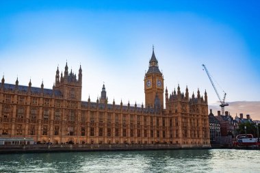 Parlamentonun ve Büyük Ben 'in ikonik evleri gün batımında güzelce aydınlatılır. Thames nehrine yukarıdaki açık mavi gökyüzü, Birleşik Krallık' ı yansıtır.