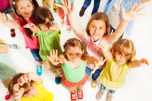 Bunch of kids lifting hands in the air — Stock Photo, Image