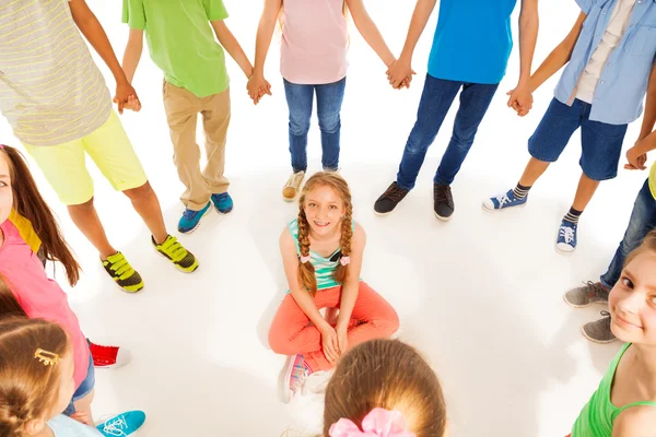 Leuk meisje zitten terwijl kinderen reel — Stockfoto