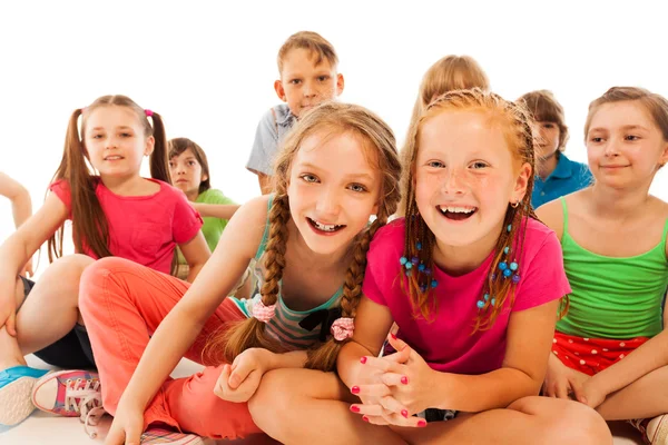 Two happy chatting girls sit in group of friends — Stock Photo, Image