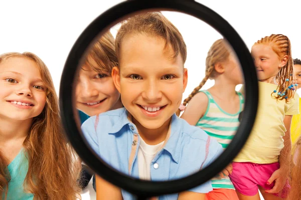 Boy through magnifier glass and with friends — Stock Photo, Image