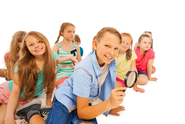 Boy searching with magnifying glass and friends — Stock Photo, Image