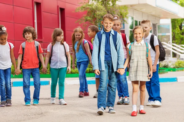 Веселые дети с рюкзаками рядом со школьным зданием — стоковое фото