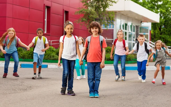 Rader av barn med ryggsäckar nära skolan promenader — Stockfoto