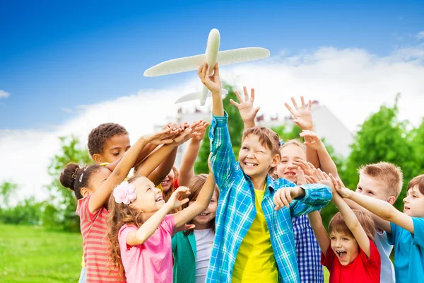 Los niños alcanzan después de juguete grande avión blanco — Foto de Stock