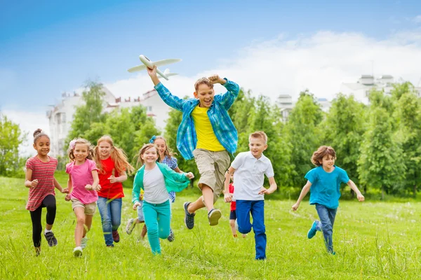 Стрибки хлопчика тримає велику іграшку літака і дітей — стокове фото