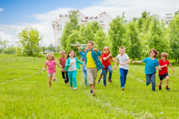 Ragazzo tiene grande bianco aeroplano giocattolo e bambini dietro — Foto Stock