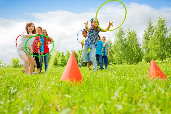 Niños jugando y lanzando aros coloridos en conos — Foto de Stock