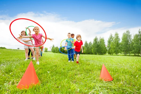 Crianças brincalhão jogando aros coloridos em cones — Fotografia de Stock