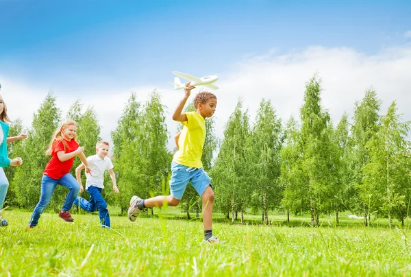 Afrikanischer Junge hält Flugzeugspielzeug und Kinder zurück — Stockfoto