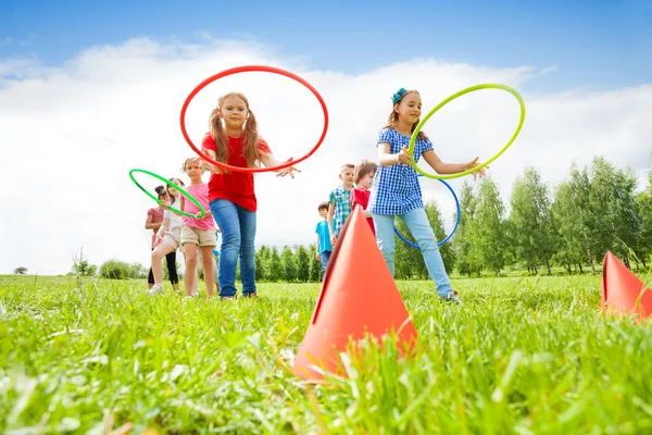 Ragazze e ragazzi felici che lanciano cerchi colorati — Foto Stock