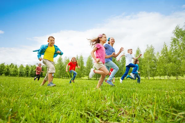 Barn kör genom gröna fält tillsammans — Stockfoto