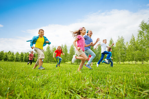 Дети бегут по зеленому полю вместе
