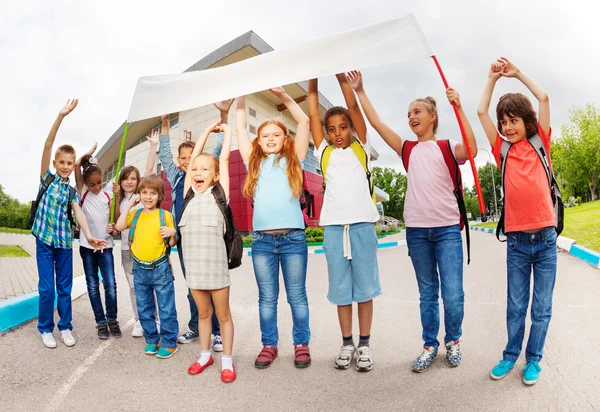 Crianças com braços para cima segurando cartaz de pé — Fotografia de Stock