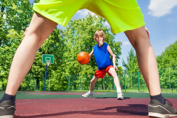 Blick zwischen zwei Beinen von Spieler und Junge mit Ball — Stockfoto