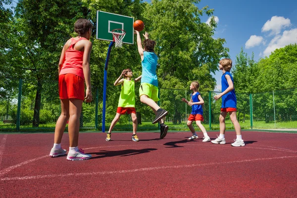 Equipe em uniformes coloridos jogando jogo de basquete — Fotografia de Stock