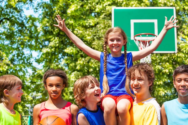 Mädchen mit erhobenen Armen auf den Schultern von Freunden nach dem Spiel — Stockfoto