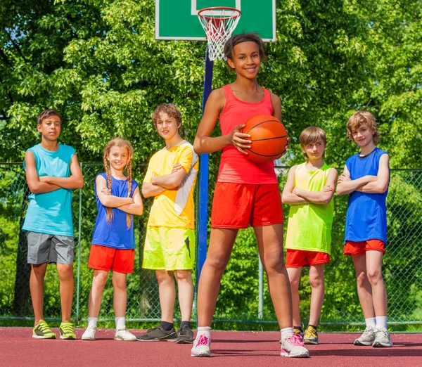 Africana chica con bola y adolescentes de pie detrás — Foto de Stock