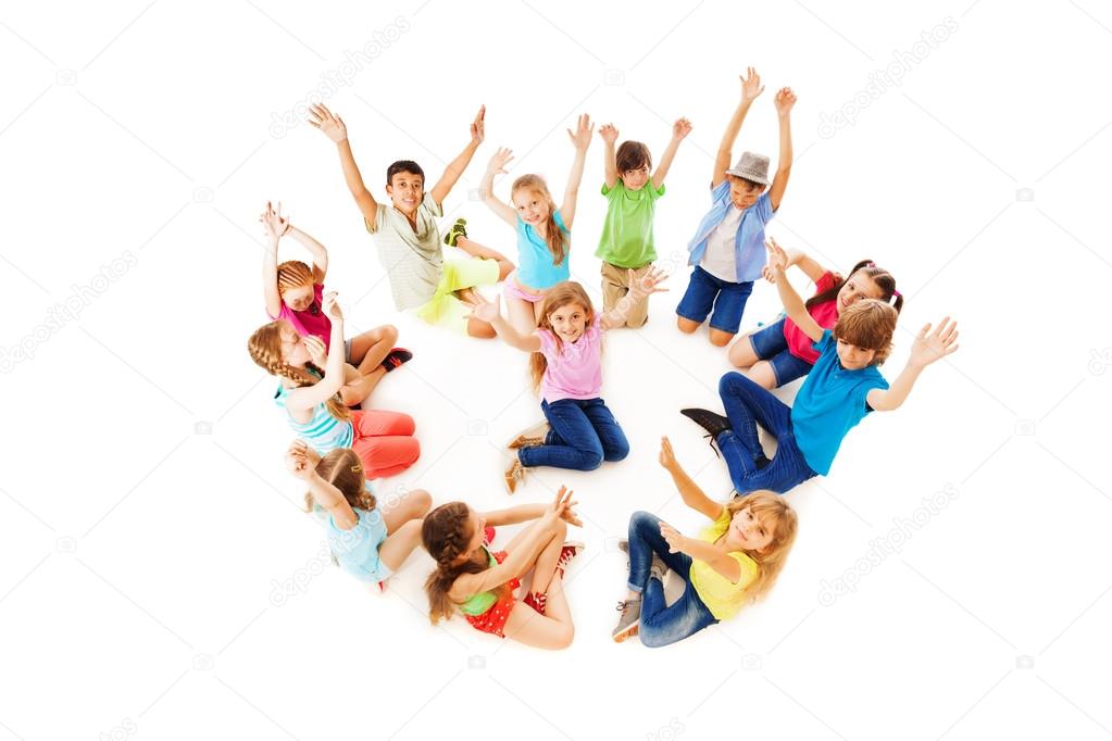 Many children in circle with boy center lift hands