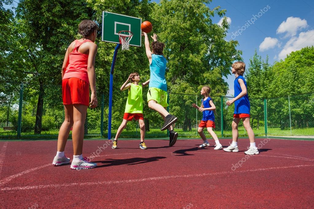Team in colorful uniforms playing basketball game Stock Photo by