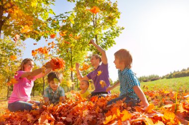 Parents and kids throw leaves in the air together