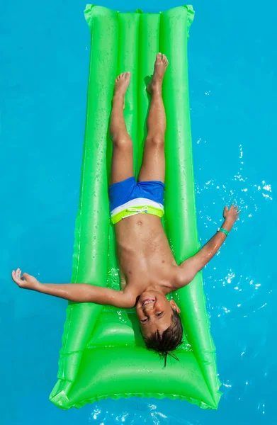 Boy relaxing on green inflatable mattress — Stock Photo, Image