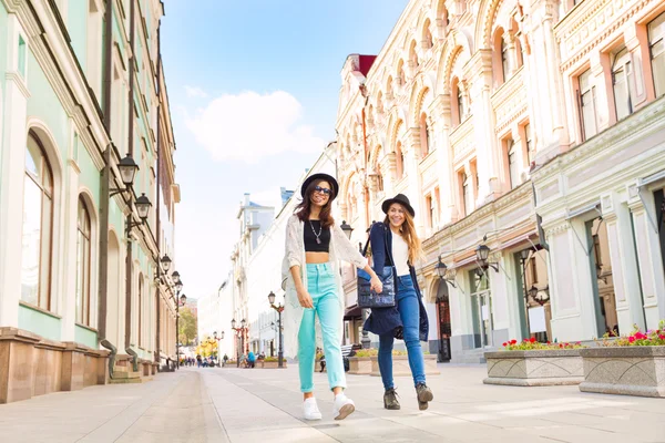 Two happy girls walking holding hands — Stock Photo, Image