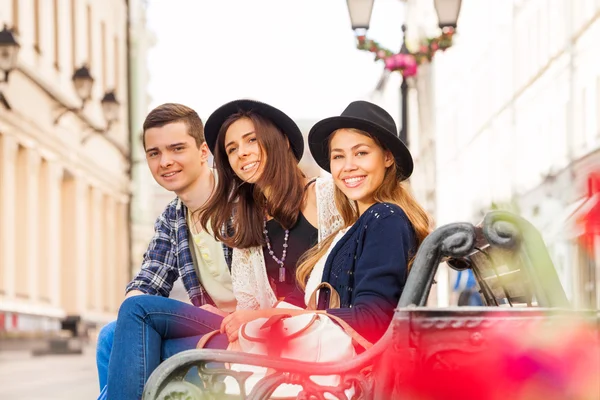 Freunde sitzen auf der Bank in der schönen Straße — Stockfoto