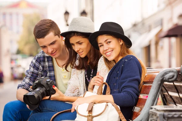 Three friends with camera sit together — Stock Photo, Image