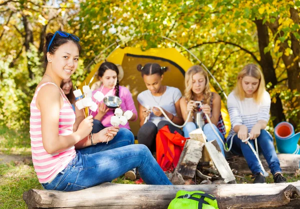 Girl holds sticks with smores sitting — Stock Photo, Image