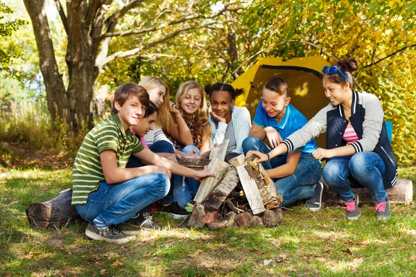 Glückliche Teenager zünden Lagerfeuer an — Stockfoto