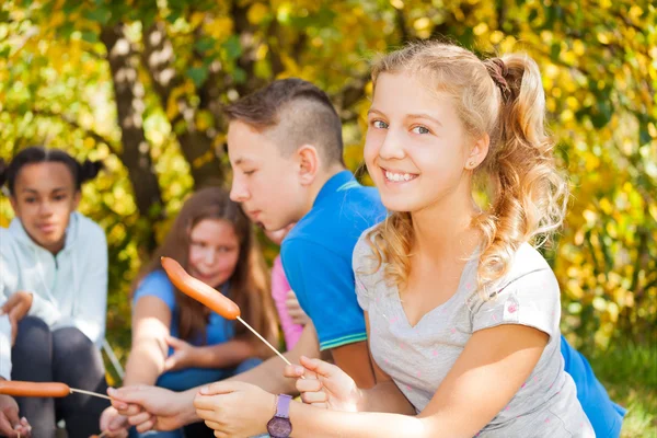 Flicka och tonåringar sitter på campingen — Stockfoto