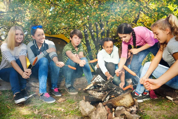 Adolescentes no acampamento grill salsichas — Fotografia de Stock