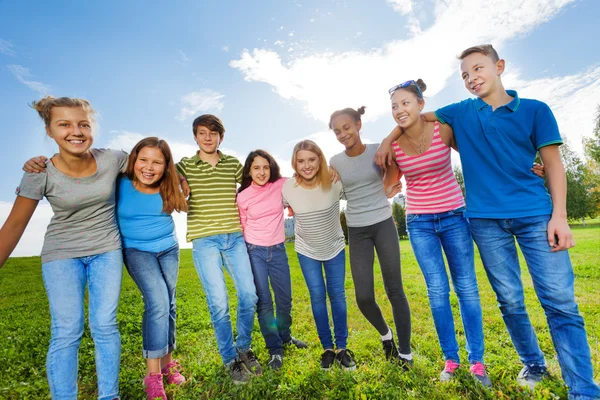 Amigos sonrientes parados en la hierba — Foto de Stock