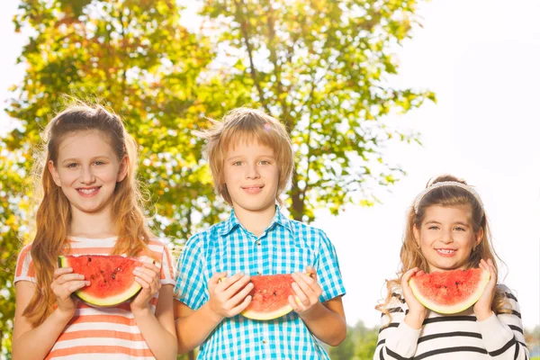 Vrienden houden watermeloen en samen eten in rij — Stockfoto