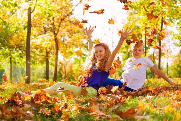 Happy boy and girl play with leaves — Stock Photo, Image