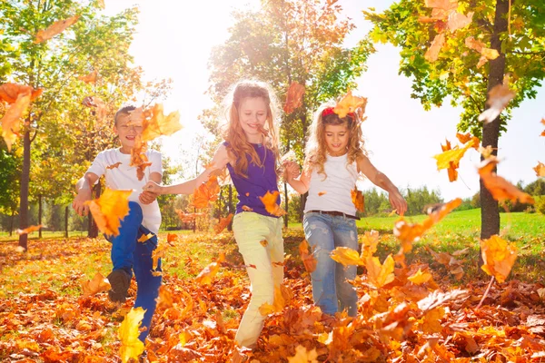 Glückliche Freunde spielen mit bunten Blättern — Stockfoto