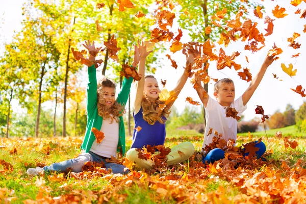 Friends playing with thrown leaves — Stock Photo, Image