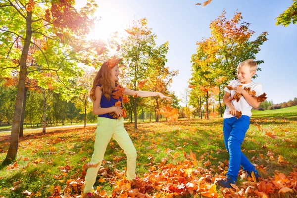 Mädchen und Junge spielen Blätter werfen — Stockfoto