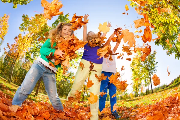 Kids playing with thrown leaves — Stock Photo, Image