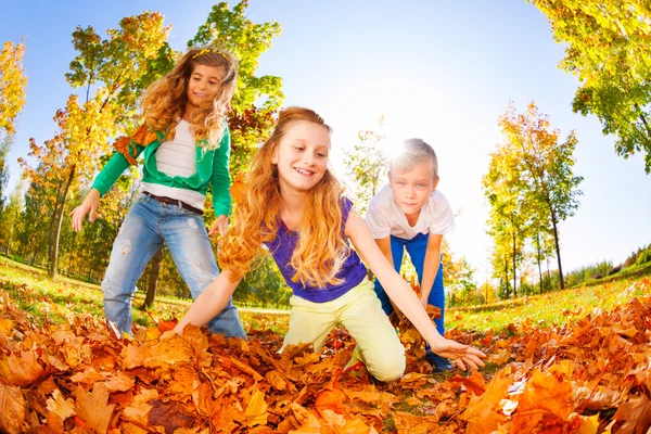 Amici felici che giocano foglie rosse — Foto Stock