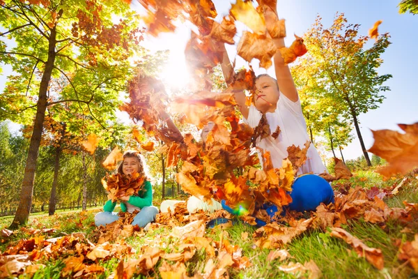 Tre amici che giocano con le foglie nella foresta — Foto Stock