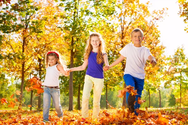 Three kids hold hands playing in the forest — Stock Photo, Image